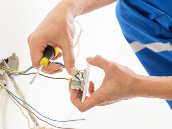 Eine Person schließt Kabel an einer Steckdose an